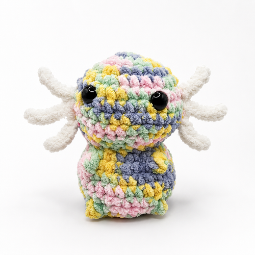 Handmade crochet axolotl plush in pastel multicolor yarn with white gills and glossy black eyes.