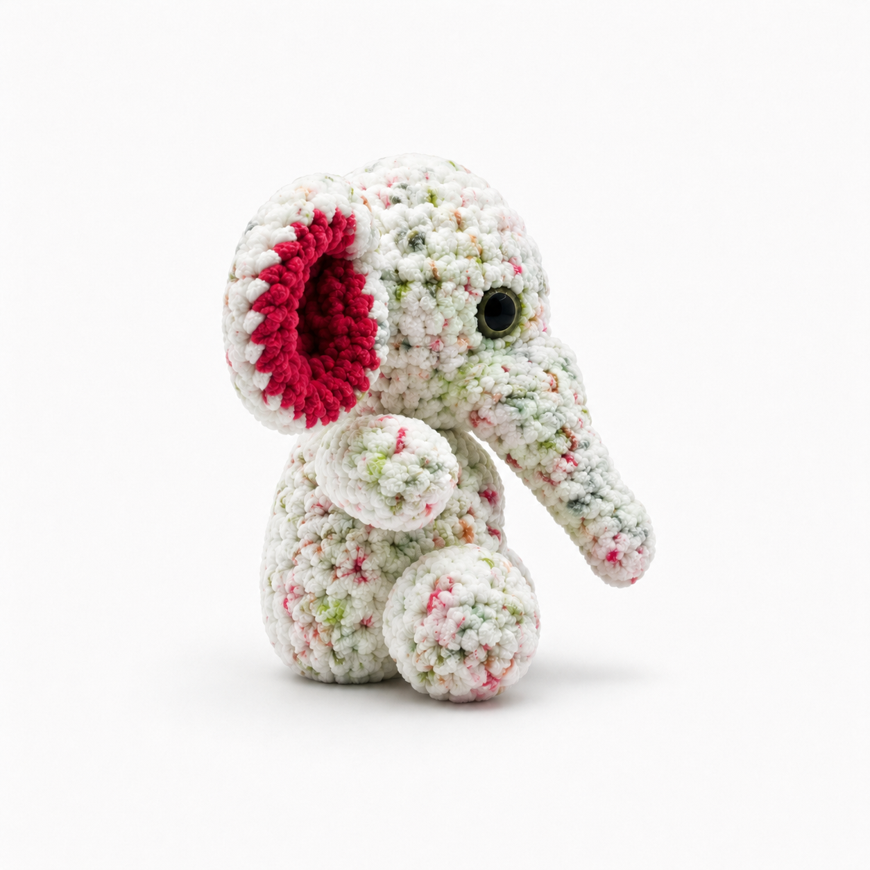 Side view of handmade crochet elephant plush showing the trunk, ear, and rounded body.